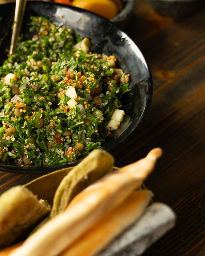 Vibrant tabouleh salad in a black bowl with fresh greens and lemon seasoning.